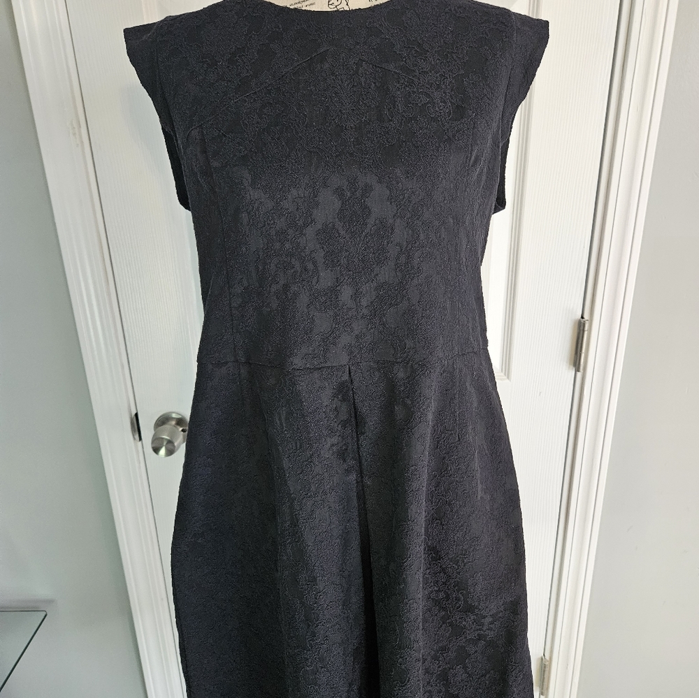 Laundry dress features black brocade material, front pleat, and pockets